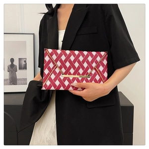 Detail of red and white checkered envelope clutch bag with gold metal trim and magnetic closure