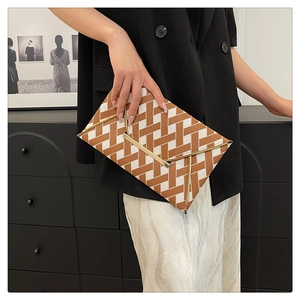 Detail of envelope clutch bag featuring brown woven texture and V-shaped gold metal trim