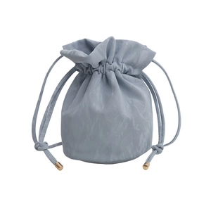 Light blue drawstring bucket bag with textured pleats and gold hardware details