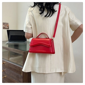 Sac à main rouge en cuir porté par un mannequin avec un design minimaliste rectangulaire