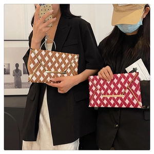 Detail of geometric weave envelope clutch with decorative gold buckle and vintage texture