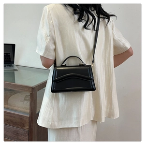 Vue arrière du modèle portant un sac à main noir minimaliste avec détails en métal doré
