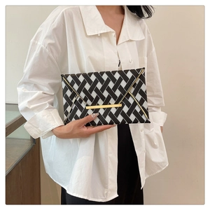 Detail of woven black and white envelope clutch with minimalist gold bar metal fastener