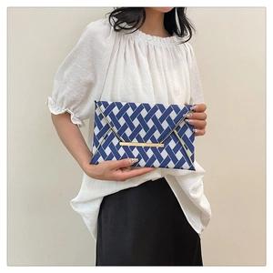 Detail view of woven envelope clutch with blue white pattern and gold metal hardware