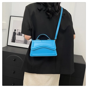Détail d'un sac à bandoulière bleu vif avec un design unique de rabat à vagues