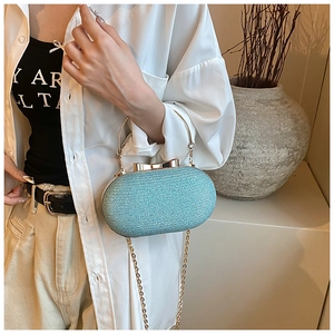 Detail of mint green glitter evening clutch bag with gold bow clasp and chain strap