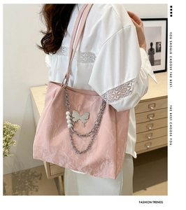 Detailed shot of pink pleated tote bag with large silver butterfly and pearl chain
