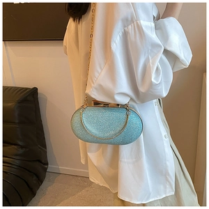 Detail of light blue sequined evening clutch with gold bow clasp and metal chain handle