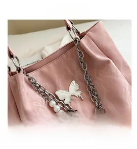 Detailed shot of pink pleated tote bag with silver butterfly charm and pearl chain