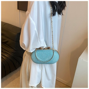 Close-up of light blue sequined clutch featuring a gold bow clasp and metal chain strap