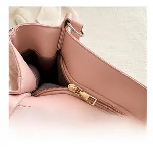 Close-up of golden metal zipper and dark brown lining on pink minimalist tote bag