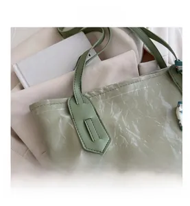 Detail of light green tote bag with crinkled texture and decorative floral silk scarf