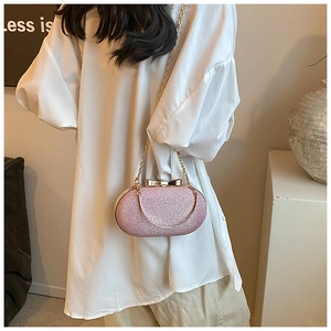 Detailed view of pink sequin evening bag with gold chain and bow clasp on white shirt