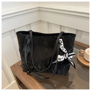 Detail of black pleated tote bag featuring a decorative fashion print silk scarf on handle