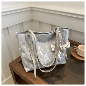 Detailed macro view of silver-grey pleated tote bag texture with fashion ribbon