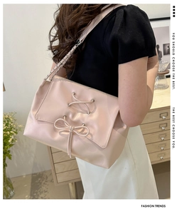Detail of soft pink faux leather tote bag with lace-up bow and metal chain strap