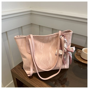 Pink pleated tote bag detail featuring a decorative fashion scarf on dark wood table