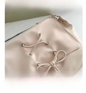 Detail of pink faux leather bag featuring lace-up bow design and silver metal chain strap