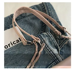 Detail of pink leather shoulder strap and silver metal chain on denim background