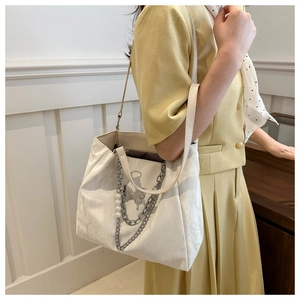 Detail of white tote bag with textured finish, silver chain, and pearl pendant decor