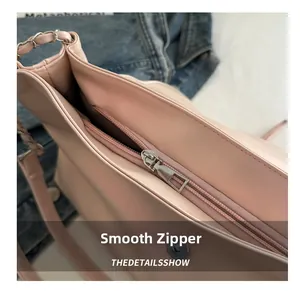 Detailed close-up of smooth silver metal zipper and chain strap on pink leather handbag
