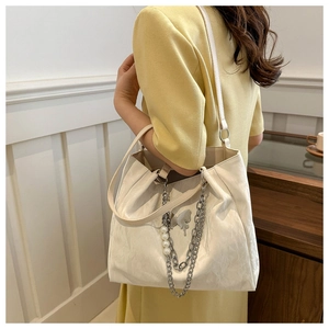 Detail of cream tote bag with ruched texture, butterfly accent and pearl metal chain