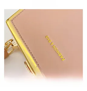 Detail of pink faux leather bag with litchi texture and gold-tone metal frame edge