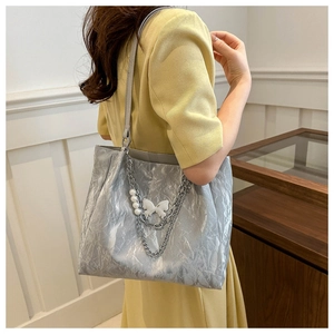 Silver wrinkled tote bag detail featuring chain accents and pearl butterfly charm