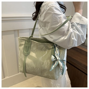 Dettaglio della borsa tote verde chiaro con texture stropicciata e foulard moda