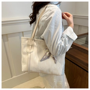 White textured tote bag with decorative silk scarf shown on shoulder in a lifestyle setting