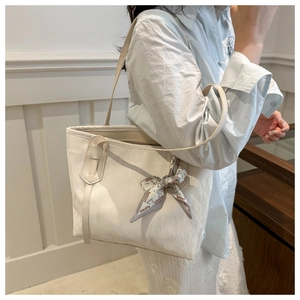 Dettaglio borsa tote bianca con elegante sciarpa di seta e sottili spalline da donna