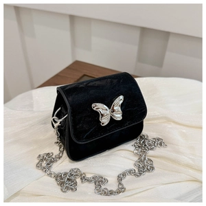 Detail of black velvet mini bag with silver butterfly clasp and fine metal chain strap