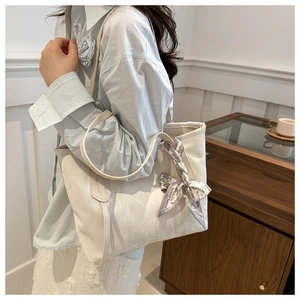 Detail of a large white tote bag with a decorative fashion scarf on a casual shoulder