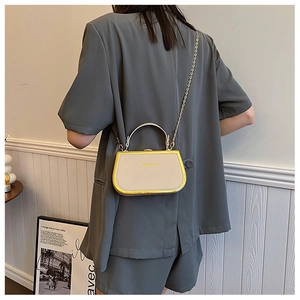 Chic beige box bag with gold frame and chain strap worn by a model in a trendy way