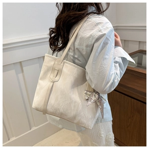 Vista dettagliata della borsa tote bianca a pieghe con foulard di seta sulla maniglia