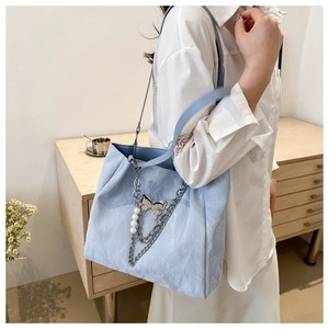 Detail of light blue tote bag with metallic chains, silver butterfly and pearls