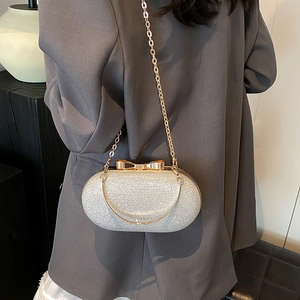 Champagne glitter evening clutch bag with golden bow clasp and chain shoulder strap