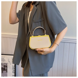 Detail of cream and yellow box bag with gold chain strap and FASHION & BAG print