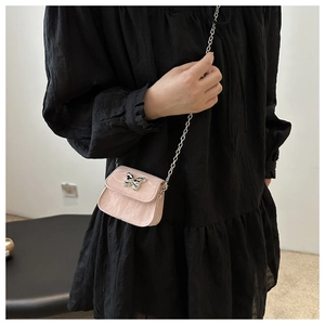 Detail of pink mini crossbody bag with silver butterfly clasp and delicate chain strap