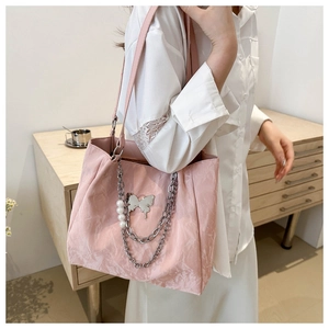 Detailed close-up of pink crinkled tote bag featuring silver butterfly and pearl chains