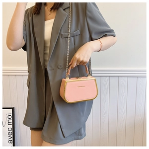 Pink chain box handbag with gold trim and polished finish styled with a grey suit