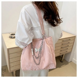 Detailed texture of pink pleated tote bag with pearl chain and butterfly metal charm