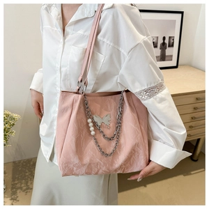 Detail of pink pleated tote bag with silver chain, white pearls and butterfly charm