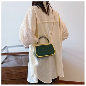 Detail of dark green vintage box bag with gold metal frame and fashion logo