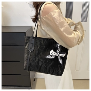 Dettaglio borsa shopper nera con trama increspata e foulard decorativo in seta stampata