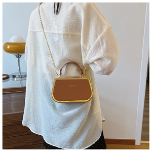 Chic caramel box bag with gold metal trim and chain strap shown on model shoulder