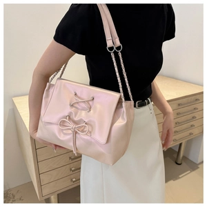 Detailed view of pink pearlescent shoulder bag with stylish bow and silver chain strap