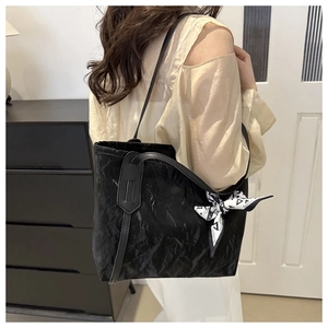 Dettaglio della borsa shopper nera con trama increspata e decorazione foulard di seta