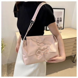 Detailed view of pale pink tote bag featuring unique drawstring bow and metal chain strap