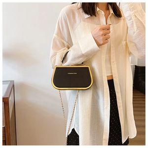 Detail view of stylish black box handbag with gold chain strap and fashion logo